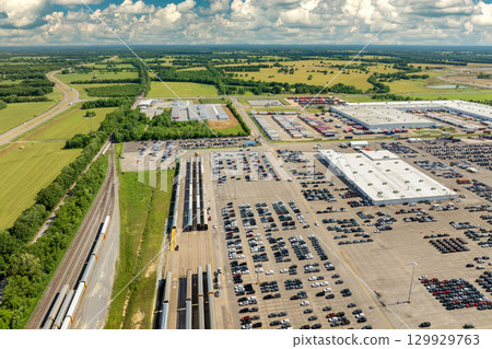 Automotive industry. Import or export of new cars by rail. Train auto racks at production factory warehouse. Vehicles for sale at logistics business parking lot 129929763