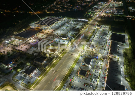 Shopping plaza stores and malls at sunset and American wide highway with many driving cars in North Port, Florida. USA retail and transportation infrastructure Shopping plaza stores and malls at sunset and American wide highway with many driving cars in North Port, Florida. USA retail and transportation infrastructure 129929796
