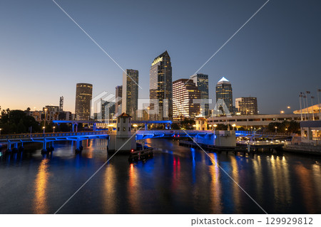 Night urban landscape of downtown district of Tampa in Florida, USA. American city skyline with brightly illuminated high commercial buildings and bridge over Hillsborough river. 129929812