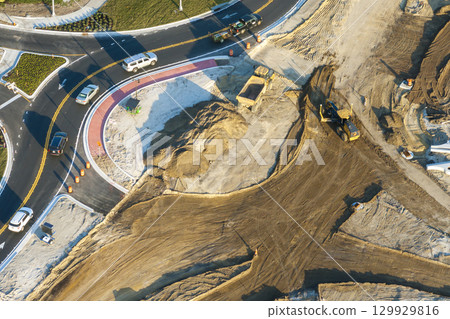 Driving traffic cars at roundabout intersection under construction. Building traffic circle on American road with moving cars 129929816