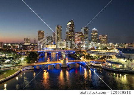 American city skyline with brightly illuminated high commercial buildings and bridge over Hillsborough river. Night urban landscape of downtown district of Tampa in Florida, USA. American city skyline with brightly illuminated high commercial buildings and bridge over Hillsborough river. Night urban landscape of downtown district of Tampa in Florida, USA. 129929818