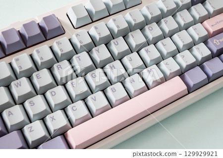Modern mechanical keyboard on blue background. Minimal style and design keyboard. Custom build keyboard with pink and green keycap. Close up Modern mechanical keyboard on blue background. Minimal style and design keyboard. Custom build keyboard with pink and green keycap. Close up 129929921