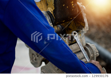 The mechanic is using a wrench to tighten a nut for maintenance. The mechanic is using a wrench to tighten a nut for maintenance. 129930176