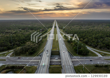 Freeway overpass junction in Florida with fast moving traffic cars and trucks in American rural area at sunset. Interstate transportation infrastructure in USA 129930189