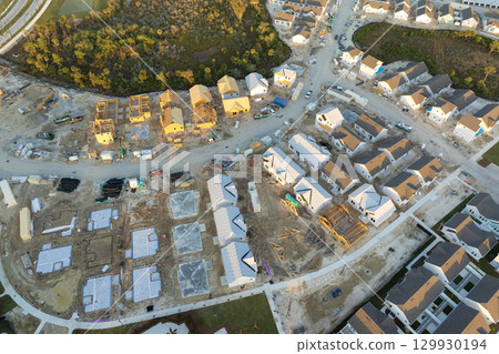 Aerial view of unfinished wooden frames of affordable houses under construction. Development of residential housing in American suburbs. Real estate market in the USA Aerial view of unfinished wooden frames of affordable houses under construction. Development of residential housing in American suburbs. Real estate market in the USA 129930194