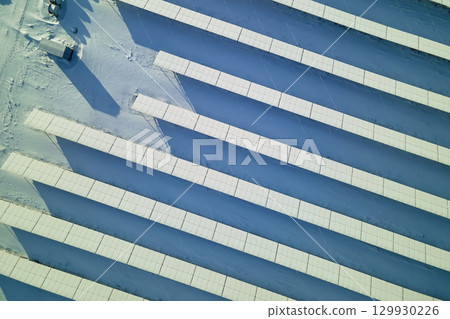 Aerial view of snow covered sustainable electric power plant with rows of solar photovoltaic panels for producing clean electrical energy. Low effectivity of renewable electricity in northern winter 129930226