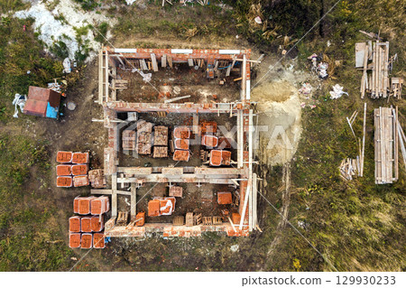 Aerial view of building site for future brick house, concrete foundation floor and stacks of yellow clay bricks for construction. Aerial view of building site for future brick house, concrete foundation floor and stacks of yellow clay bricks for construction. 129930233