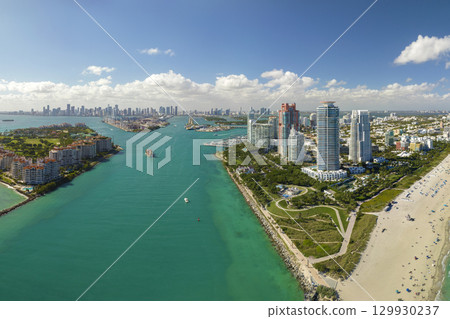 Tourism infrastructure in southern USA. South Beach sandy surface with tourists relaxing on hot Florida sun. Miami Beach city with high luxury hotels and condos 129930237