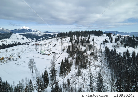 Winter landscape with small village houses between snow covered forest in cold mountains Winter landscape with small village houses between snow covered forest in cold mountains 129930242