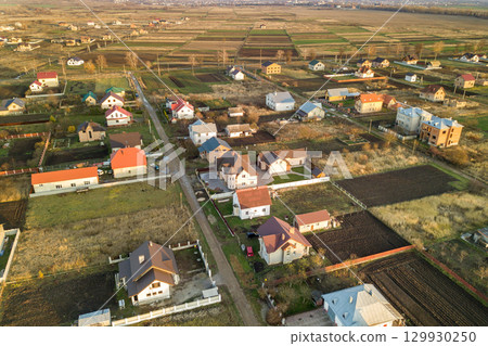Aerial landscape of small town or village with rows of residential homes and green trees. Aerial landscape of small town or village with rows of residential homes and green trees. 129930250