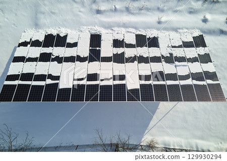 Aerial view of snow melting from covered solar photovoltaic panels at sustainable electric power plant for producing clean electrical energy. Low effectivity of renewable electricity in winter 129930294