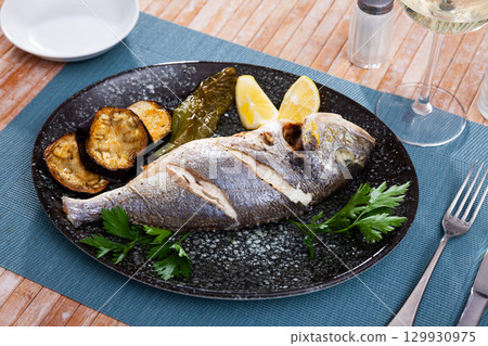 Fried dorada with baked pepper, eggplant, fresh parsley and lemon 129930975