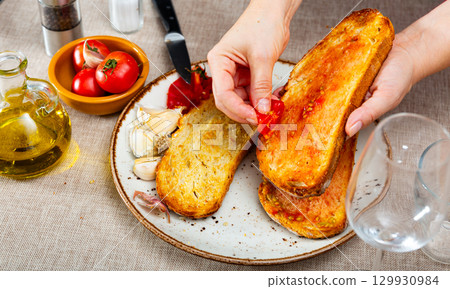 Female hands preparing pa amb tomaquet with ripe tomato 129930984