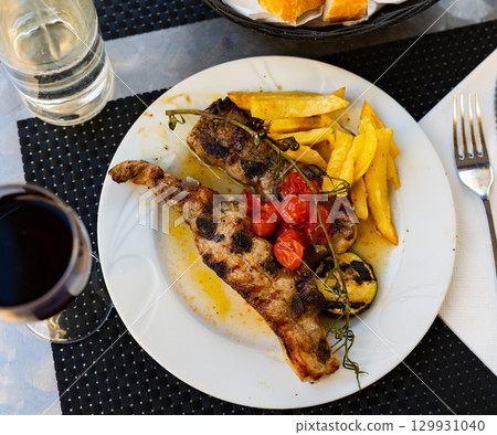 Spanish cuisine. Grilled beef ribs with a side dish of fresh tomatoes and fried potatoes Spanish cuisine. Grilled beef ribs with a side dish of fresh tomatoes and fried potatoes 129931040