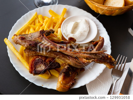 Baked lamb ribs with french fries and aioli sauce Baked lamb ribs with french fries and aioli sauce 129931058