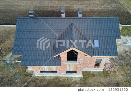 Aerial view of house roof top covered with ceramic shingles. Tiled covering of building under construction 129931260