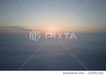 Aerial view from airplane window at high altitude of dense puffy cumulus clouds flying in evening 129931282