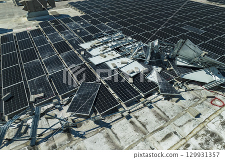Broken down photovoltaic solar panels destroyed by hurricane Ian winds mounted on industrial building roof for producing green ecological electricity. Consequences of natural disaster Broken down photovoltaic solar panels destroyed by hurricane Ian winds mounted on industrial building roof for producing green ecological electricity. Consequences of natural disaster 129931357