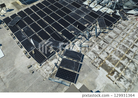 Top view of destroyed by hurricane Ian photovoltaic solar panels mounted on industrial building roof for producing green ecological electricity. Consequences of natural disaster in Florida Top view of destroyed by hurricane Ian photovoltaic solar panels mounted on industrial building roof for producing green ecological electricity. Consequences of natural disaster in Florida 129931364