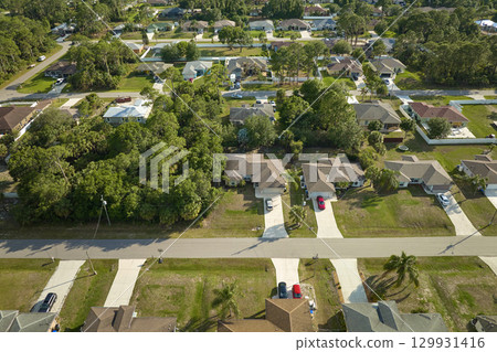 Aerial view of suburban landscape with private homes between green palm trees in Florida quiet residential area 129931416