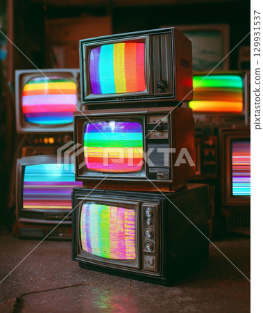 Vintage televisions stacked with colorful screens illuminating a retro setting featuring vibrant patterns 129931537