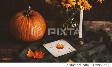 Autumn still life with Halloween pumpkin, candle, fall decor creates a cozy atmosphere. Autumnal scene features yellow fall flowers, and greeting card. Thanksgiving season This is AI-generated item 129931547