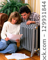 A Couple Engaging in Reviewing Important Documents by a Radiator in Their Cozy Living Room Space 129931844