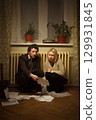 A Couple Engaged in Analyzing Important Documents in a Cozy, Dimly Lit Room Together 129931845