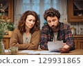 A Couple Engaged in Analyzing Household Bills Together in a Cozy Kitchen Setting and Atmosphere 129931865