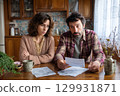 A Concerned Couple Thoroughly Reviewing Their Bills and Financial Obligations at Home Together 129931871