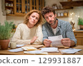 A Concerned Couple Engaged in a Detailed Review of Their Financial Statements at Home Together 129931887