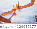 Group of friends clinking glasses with cocktails on the beach. Tattoos on arms 129932177