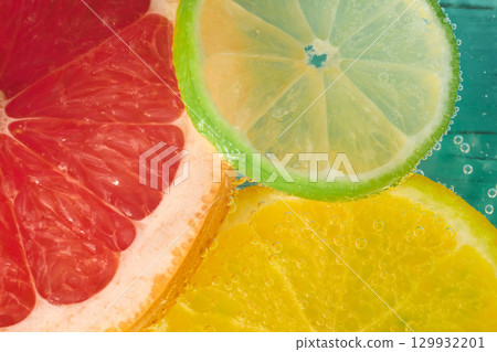 Slices of grapefruit, lemon, and lime float in sparkling water, showcasing bright colors and bubbles 129932201