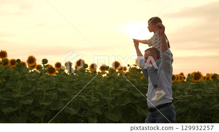 Father and daughter in sunflower field at sunset, happy family in summer, dad carrying child on shoulders, sunny day in nature, enjoying time together outdoors, bonding in the countryside, beautiful Father and daughter in sunflower field at sunset, happy family in summer, dad carrying child on shoulders, sunny day in nature, enjoying time together outdoors, bonding in the countryside, beautiful 129932257