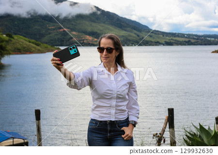 Female tourist taking pictures at the biggest artificial lake in Colombia called Calima Lake located on the mountains of Darien at the region of Valle del Cauca 129932630