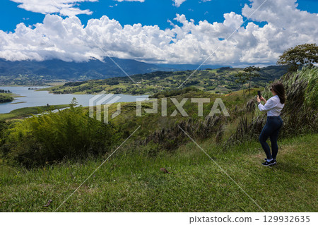 Female tourist taking pictures at the biggest artificial lake in Colombia called Calima Lake located on the mountains of Darien at the region of Valle del Cauca 129932635