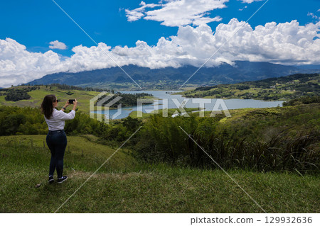 Female tourist taking pictures at the biggest artificial lake in Colombia called Calima Lake located on the mountains of Darien at the region of Valle del Cauca 129932636