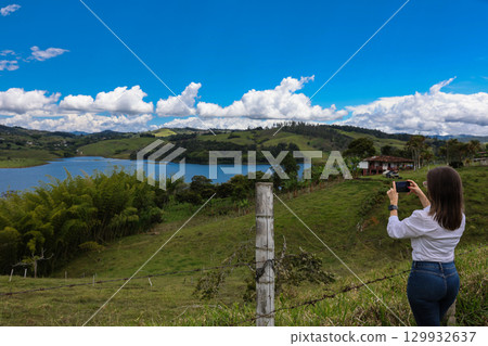 Female tourist taking pictures at the biggest artificial lake in Colombia called Calima Lake located on the mountains of Darien at the region of Valle del Cauca 129932637