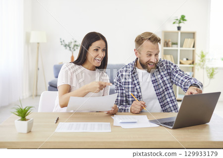 Happy family couple receive payment or get tax refund while doing financial paperwork Happy family couple receive payment or get tax refund while doing financial paperwork 129933179