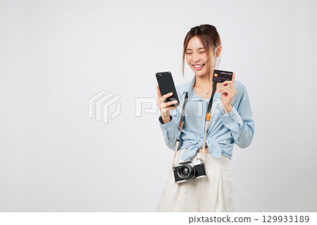 Travel phone and travel photo camera with happy Traveler tourist Asian woman shopping. Credit card bank ready, mobile in hand, enjoying internet shopping during vacation. isolated white background Travel phone and travel photo camera with happy Traveler tourist Asian woman shopping. Credit card bank ready, mobile in hand, enjoying internet shopping during vacation. isolated white background 129933189