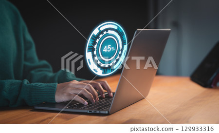 Female user working on a laptop, downloading updates with slow internet from Wi-Fi. Loading symbol highlights delays in file retrieval, reflecting digital software management and connectivity issues. 129933316