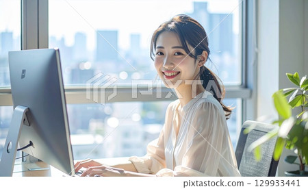 Portrait of a young Japanese woman typing on a computer at a desk by the window Portrait of a young Japanese woman typing on a computer at a desk by the window 129933441