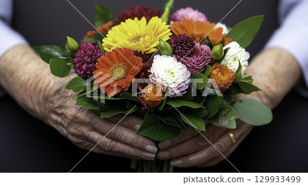 Colorful Floral Bouquet with Hands Holding Vibrant Flowers Against Dark Background 129933499