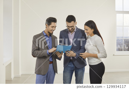 Young happy couple reaching agreement and going to sign a deal with a real estate agent. 129934117