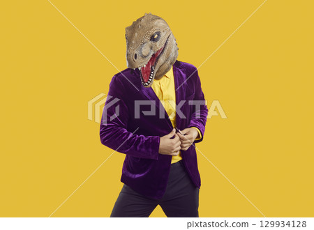 Portrait of funny man wearing purple suit and dinosaur mask posing in fashion studio 129934128