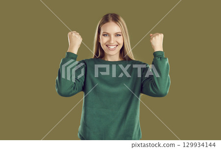 Happy blonde young woman clenching her fists feeling happy 129934144