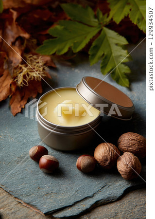 Shea Butter Balm in Open Tin on Slate with Nuts and Leaves 129934507