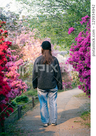 Ashikaga Flower Park: A woman walking among azaleas and double cherry blossoms 129934942