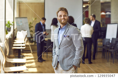 Happy confident bearded business man looking at the camera and smiling in the office. Happy confident bearded business man looking at the camera and smiling in the office. 129935047