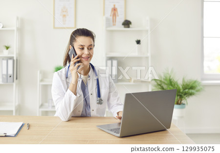 Doctor Or Nurse On Phone With Patient And Using Laptop 129935075